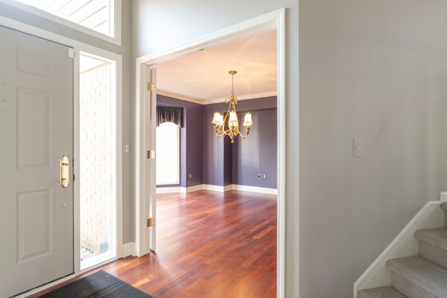 foyer entrance with baseboards, a chandelier, stairway, ornamental molding, and wood finished floors