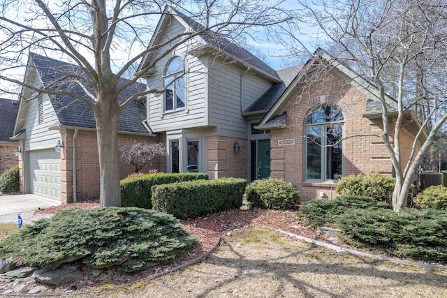 traditional-style house featuring concrete driveway, brick siding, a garage, and roof with shingles