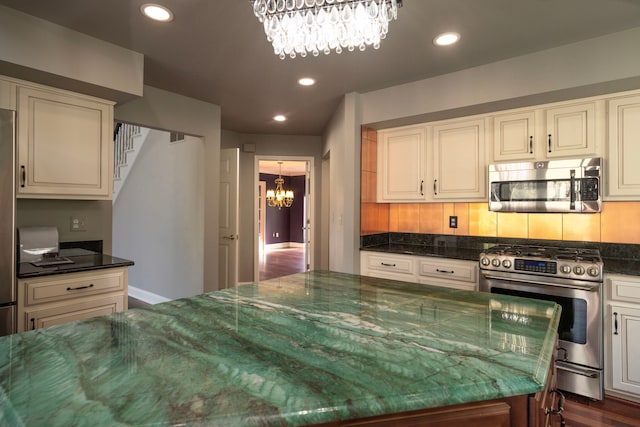 kitchen with recessed lighting, stainless steel appliances, a notable chandelier, and dark stone countertops