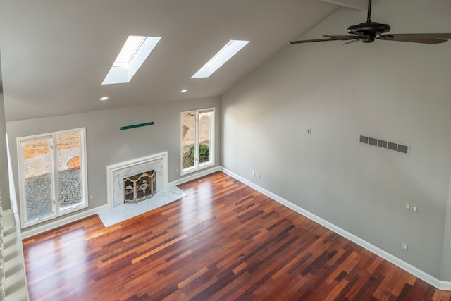 unfurnished living room featuring visible vents, lofted ceiling with skylight, wood finished floors, and a high end fireplace