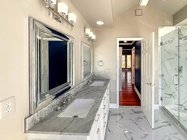 full bath with a sink, a marble finish shower, marble finish floor, and vaulted ceiling