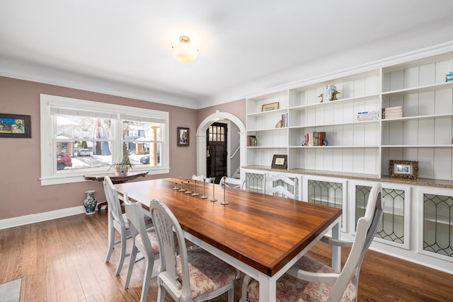 dining space with baseboards, arched walkways, and wood-type flooring