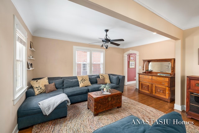 living room featuring ornamental molding, baseboards, a ceiling fan, and wood finished floors