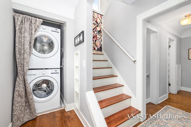 laundry area with laundry area, stacked washing maching and dryer, baseboards, and wood finished floors