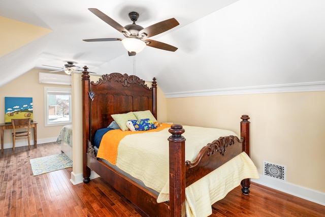 bedroom with a wall unit AC, baseboards, visible vents, lofted ceiling, and hardwood / wood-style flooring