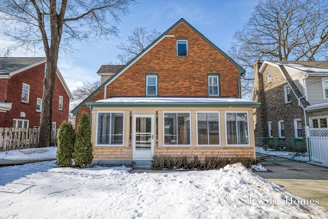 snow covered property featuring fence and a sunroom