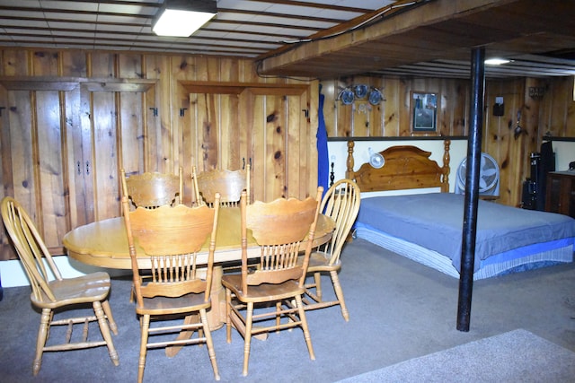 carpeted dining space featuring wooden walls