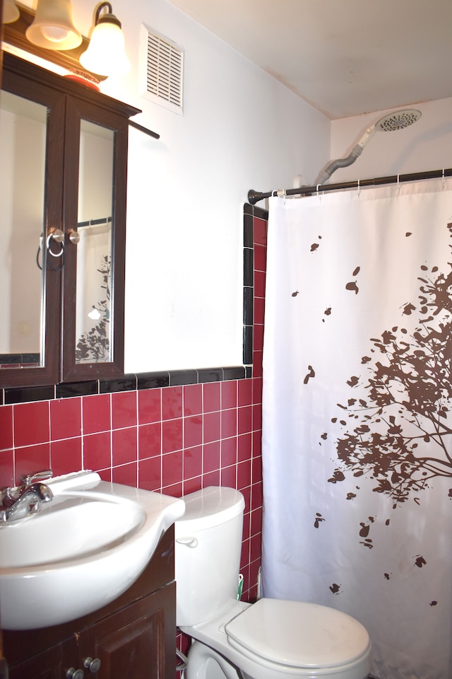 bathroom featuring visible vents, toilet, vanity, a shower with curtain, and tile walls