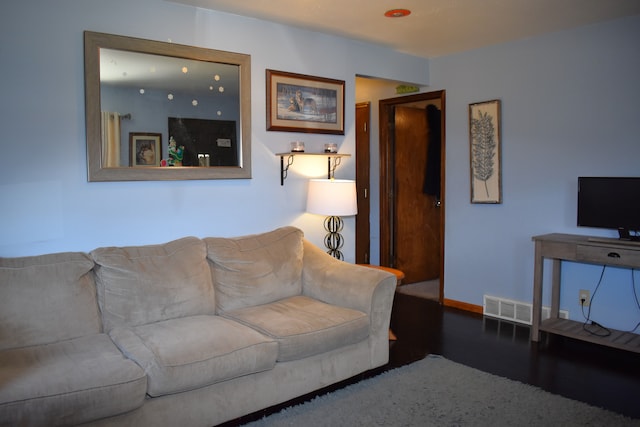 living room with wood finished floors, visible vents, and baseboards