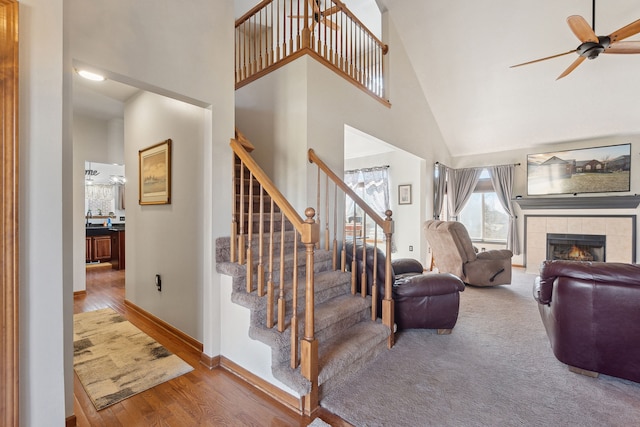 511 State St, Oxford, MI 48371 - stairs with a towering ceiling, a ceiling fan, a fireplace, wood finished floors, and baseboards