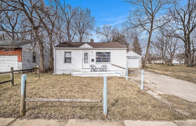 view of front of home featuring fence, concrete driveway, a chimney, a garage, and an outdoor structure