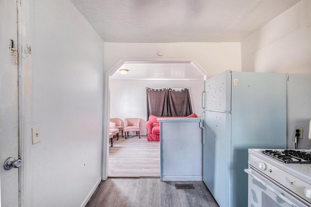 kitchen featuring visible vents, wood finished floors, white gas range, and baseboards