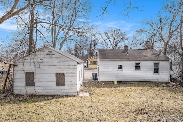 rear view of house with a lawn, a chimney, and an outdoor structure