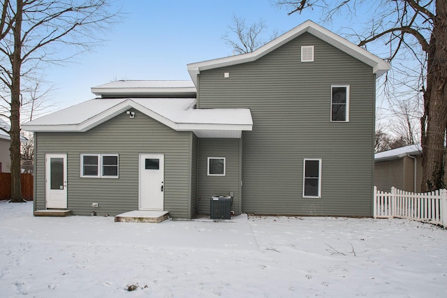 snow covered back of property with central air condition unit and fence