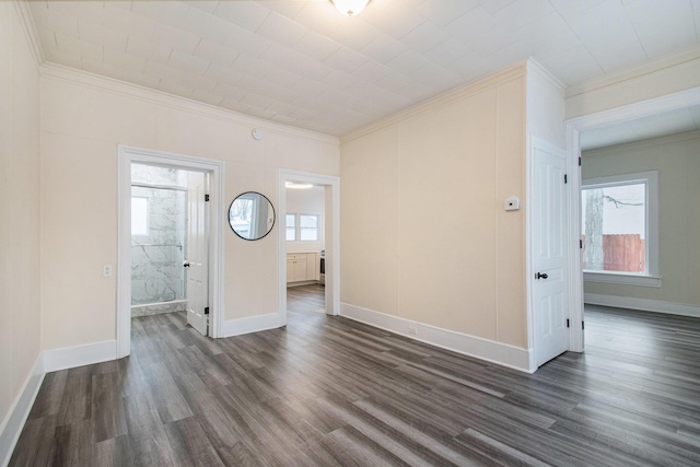 unfurnished room featuring dark wood-type flooring, baseboards, and ornamental molding
