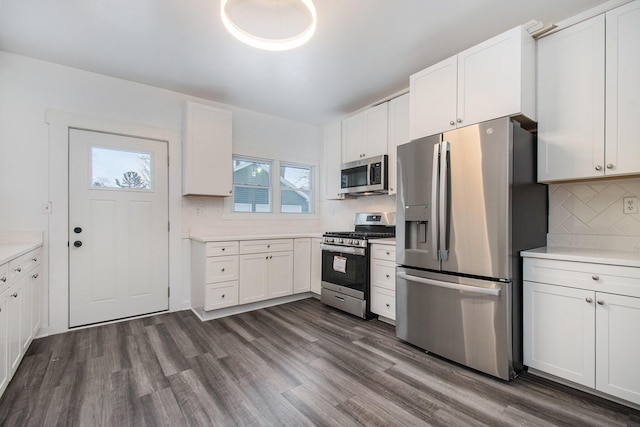 kitchen with dark wood finished floors, light countertops, appliances with stainless steel finishes, white cabinetry, and tasteful backsplash