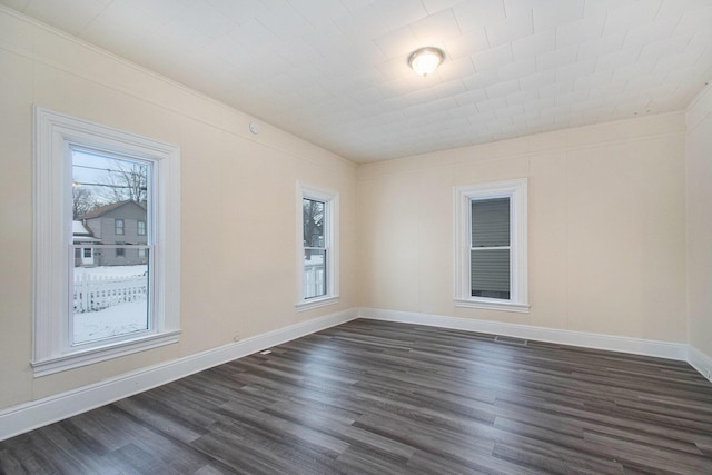 empty room featuring dark wood finished floors, a healthy amount of sunlight, and baseboards