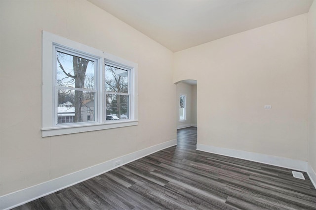 empty room with baseboards, arched walkways, lofted ceiling, and dark wood-style floors