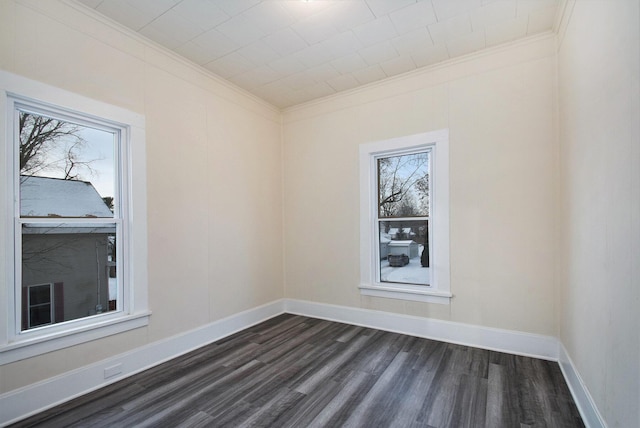 spare room featuring crown molding, baseboards, and dark wood-style flooring