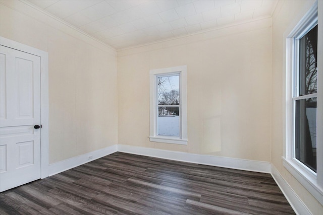 spare room featuring dark wood-style floors, baseboards, and ornamental molding