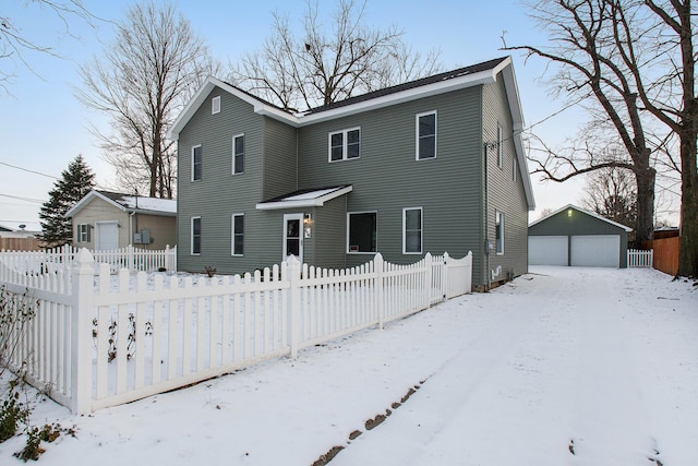 view of front of house featuring a fenced front yard, a detached garage, and an outbuilding