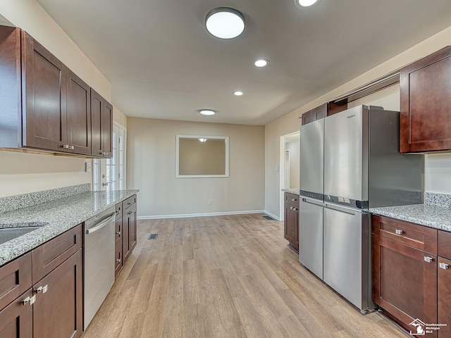 kitchen with dark brown cabinetry, light wood-style flooring, and appliances with stainless steel finishes