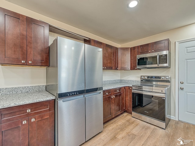 kitchen with recessed lighting, light stone countertops, light wood-style floors, and appliances with stainless steel finishes