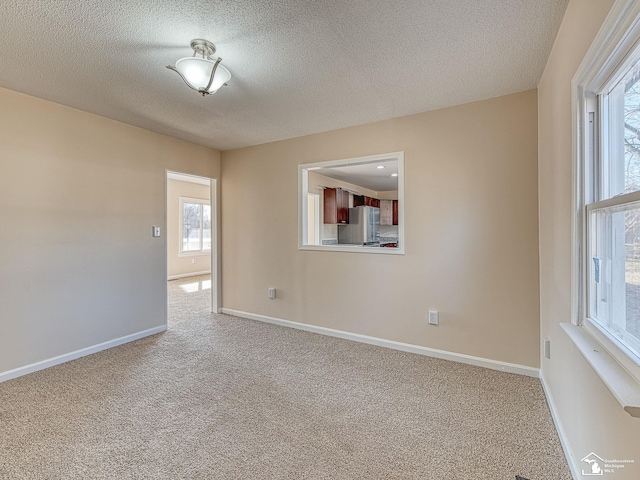 spare room with carpet flooring, a textured ceiling, and baseboards