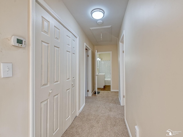 corridor featuring baseboards, attic access, and carpet