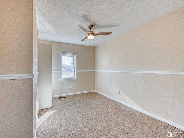 unfurnished room with visible vents, a textured ceiling, carpet flooring, baseboards, and ceiling fan