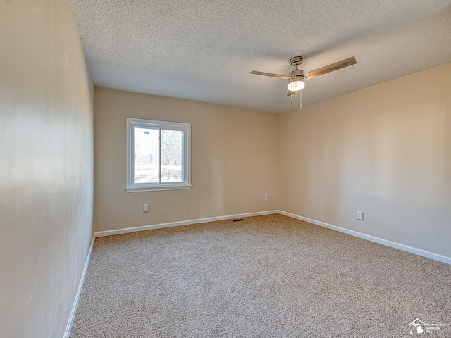 carpeted spare room featuring visible vents, a ceiling fan, baseboards, and a textured ceiling