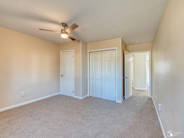 unfurnished bedroom with carpet, baseboards, ceiling fan, a closet, and a textured ceiling