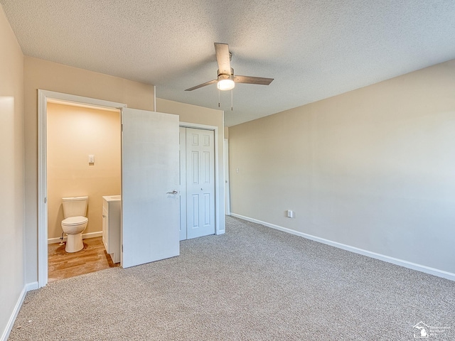 unfurnished bedroom featuring a closet, connected bathroom, baseboards, and carpet floors