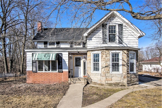 view of front of home with stone siding and a chimney