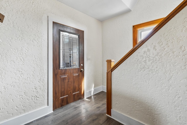 foyer entrance featuring baseboards, dark wood-type flooring, stairs, and a textured wall