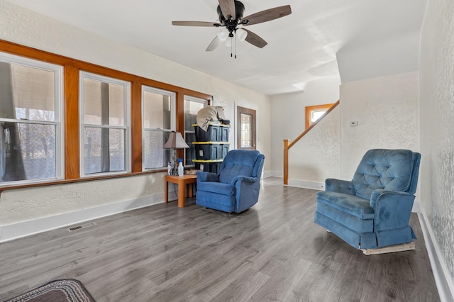 sitting room with visible vents, wood finished floors, and a textured wall