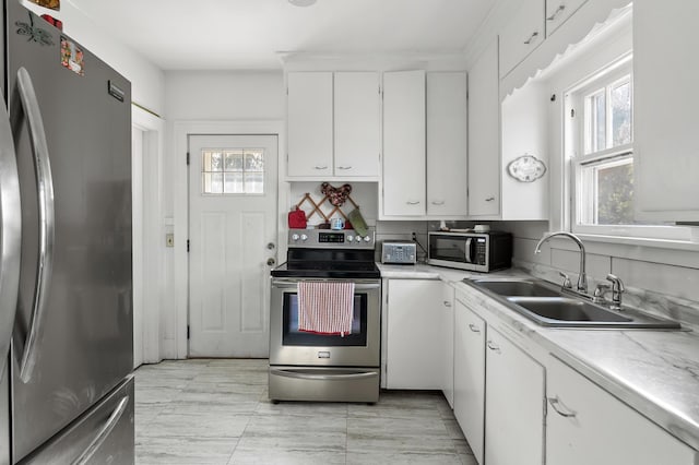 kitchen featuring a toaster, a sink, stainless steel appliances, light countertops, and white cabinetry