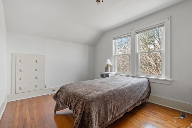 bedroom with lofted ceiling, baseboards, and wood-type flooring