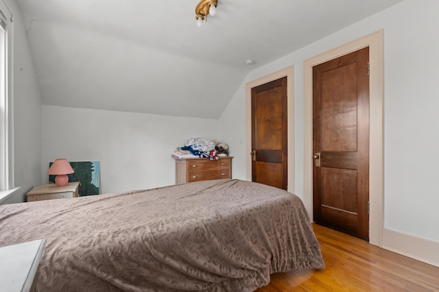 bedroom with light wood-style floors and vaulted ceiling