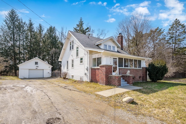 view of front of house with an outbuilding, a front yard, a porch, a chimney, and brick siding