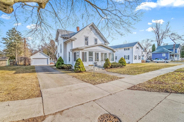 view of front of house featuring a detached garage, a front lawn, a residential view, a chimney, and an outbuilding