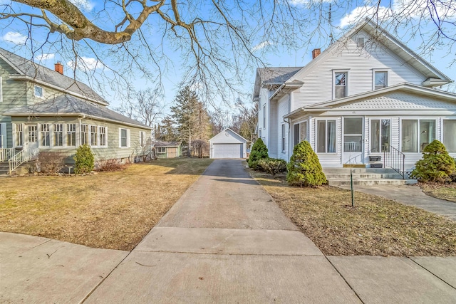 view of home's exterior with an outbuilding, a chimney, entry steps, a garage, and a lawn