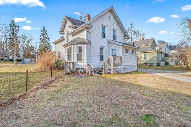 view of front of home with a chimney, central AC, a front yard, and fence