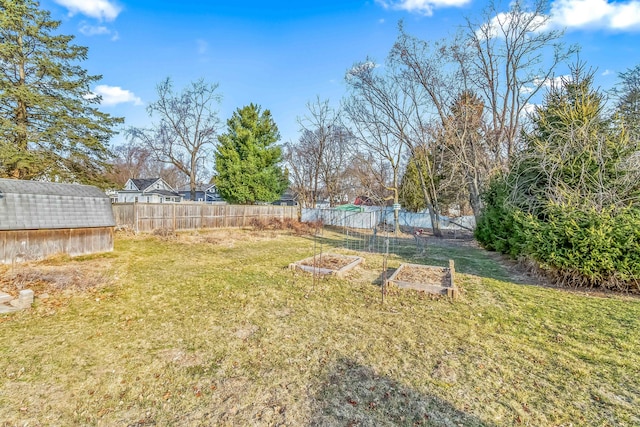 view of yard with an outbuilding, a storage unit, a vegetable garden, and fence