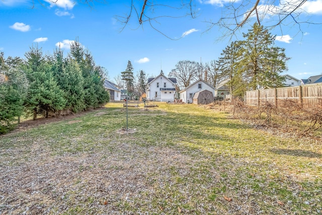 view of yard featuring an outbuilding, a storage shed, and fence