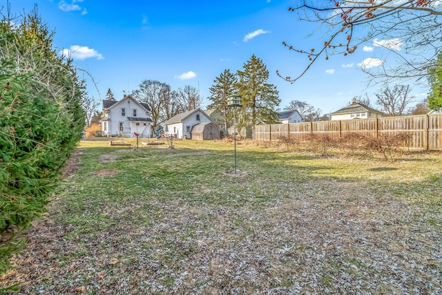 view of yard featuring a storage unit, an outdoor structure, and fence