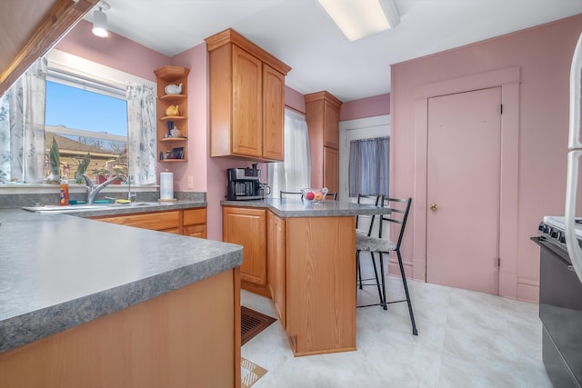 kitchen with a peninsula, a sink, stove, dark countertops, and a kitchen breakfast bar