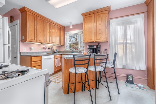 kitchen with a kitchen island, light floors, a breakfast bar, white appliances, and a sink