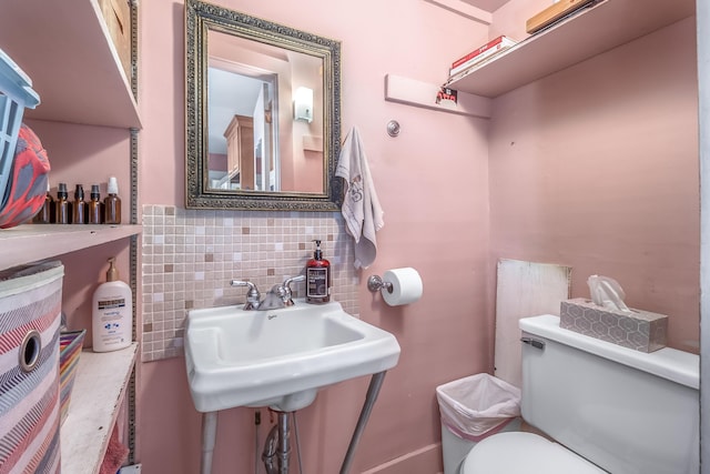 bathroom featuring decorative backsplash, toilet, and a sink