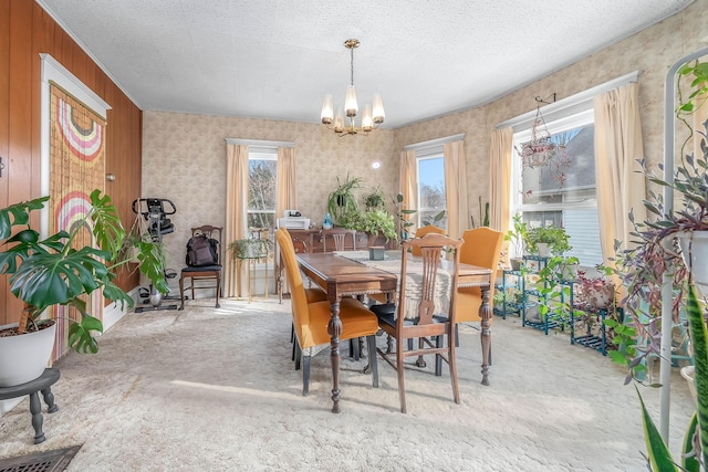 dining room with a healthy amount of sunlight, a textured ceiling, carpet, and an inviting chandelier